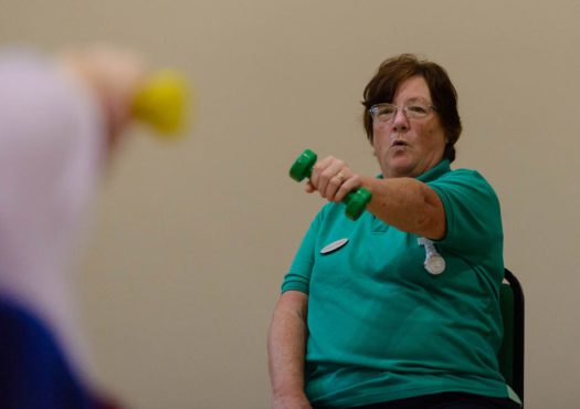 A woman taking part in a seated exercise class