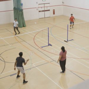group of people playing badminton in a sports hall