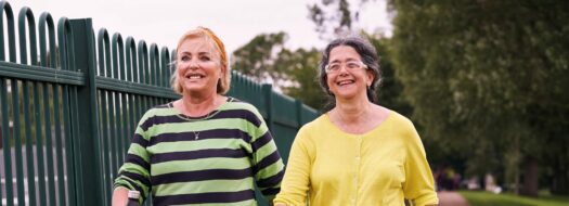 two ladies walking in park smiling