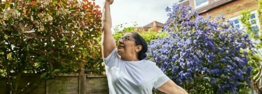 person in garden stretching arms in air