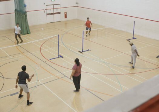 group of people playing badminton in a sports hall