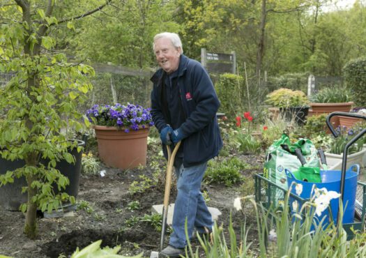 man using a spade to dig in a garden