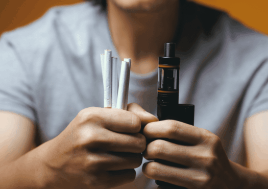 Person holding cigarettes and vape