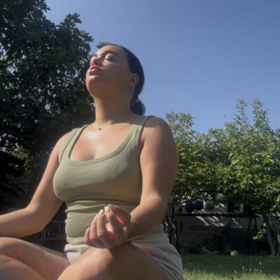 Isobel sat in a yoga pose on a mat in the garden